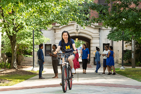 A student riding a bike through central campus