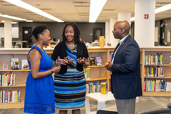 Black faculty members having a discussion in a library
