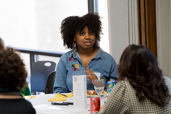 A Black female student speaking at a round table